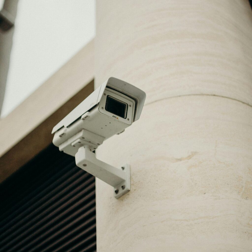 Close-up of a CCTV camera on a concrete building, symbolizing security and technology.